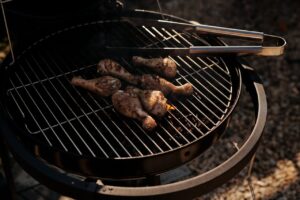 Alcuni cosciotti di pollo che si stanno cuocendo in una Griglia tonda per barbecue in acciaio cromato di BBGrilll
